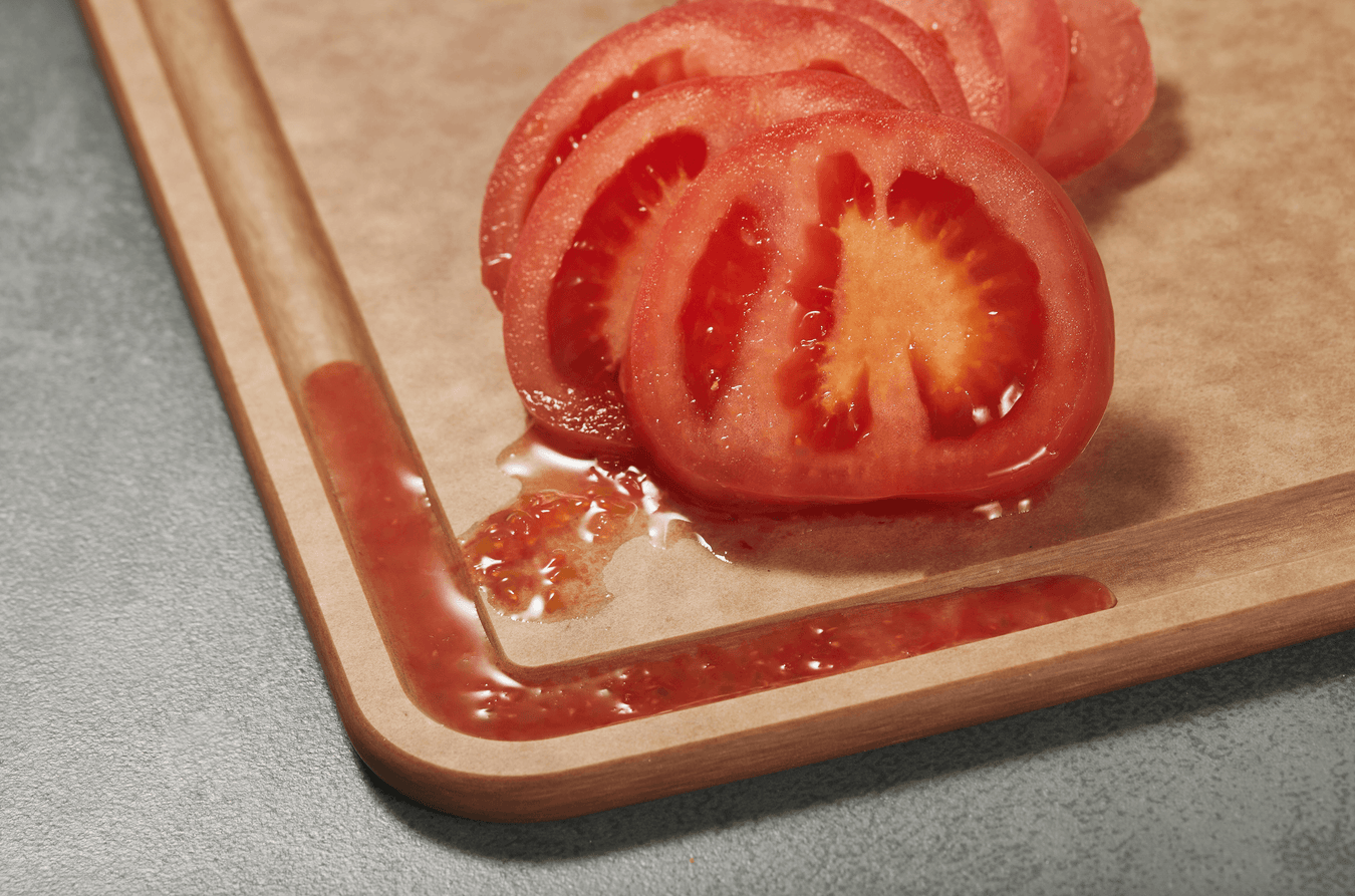 Elihome wood fiber cutting board with deep juice groove catching tomato juice from freshly sliced tomatoes