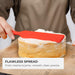 Close-up of an Elihome red skinny silicone spatula spreading cream frosting on a cake layer to demonstrate control. Text reads: "Flawless Spread. From creams to jams—smooth, clean, precise."