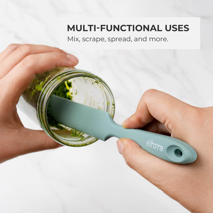 Hands using an Elihome Tiffany Blue skinny silicone spatula to scrape green sauce from a jar, demonstrating its versatility.