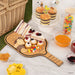 Wooden platter with assorted finger foods, including sandwiches and pastries, on a white surface.