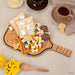 Wooden paddle with snacks including cookies, popcorn, and candy on a neutral background.