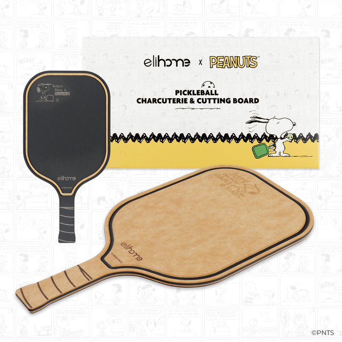 Two pickleball paddles with a 'elihome x Peanuts' pickleball charcuterie & cutting board in the background.