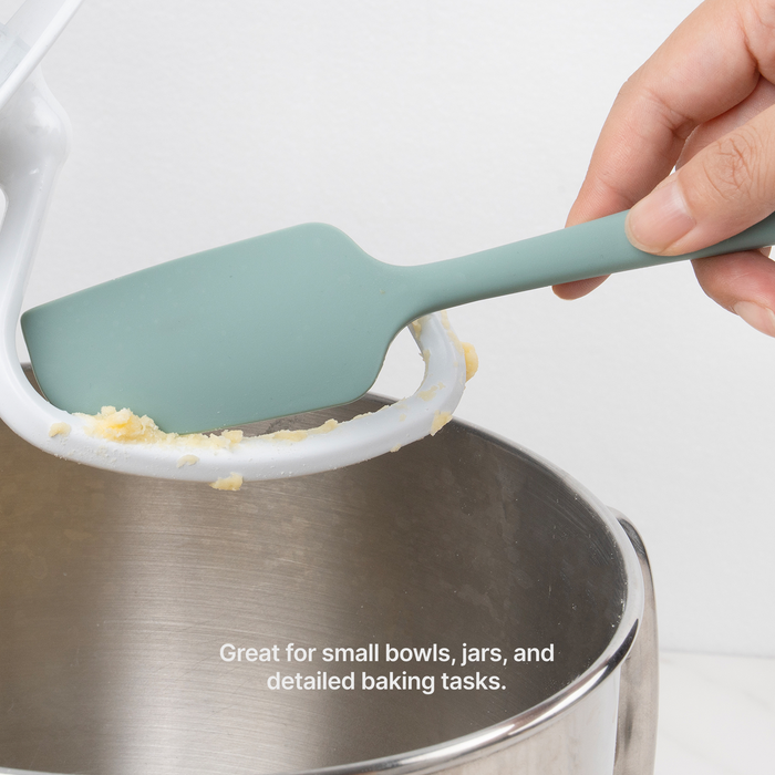 Hand using an Elihome Mini silicone spatula in Sage Green to scrape batter from the rim of a stand mixer bowl, great for small bowls, jars and detailed baking tasks