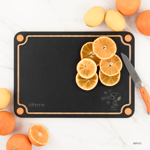 Black side of the Elihome x Peanuts 4-in-1 cutting board with sliced oranges, a paring knife and fresh citrus