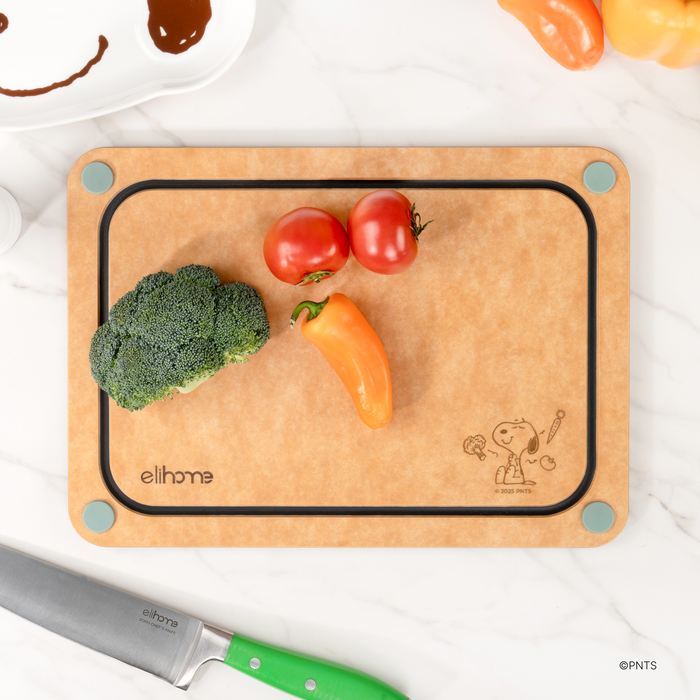 Natural side of the Elihome x Peanuts 4-in-1 cutting board with broccoli, tomatoes and a bell pepper next to a chef knife