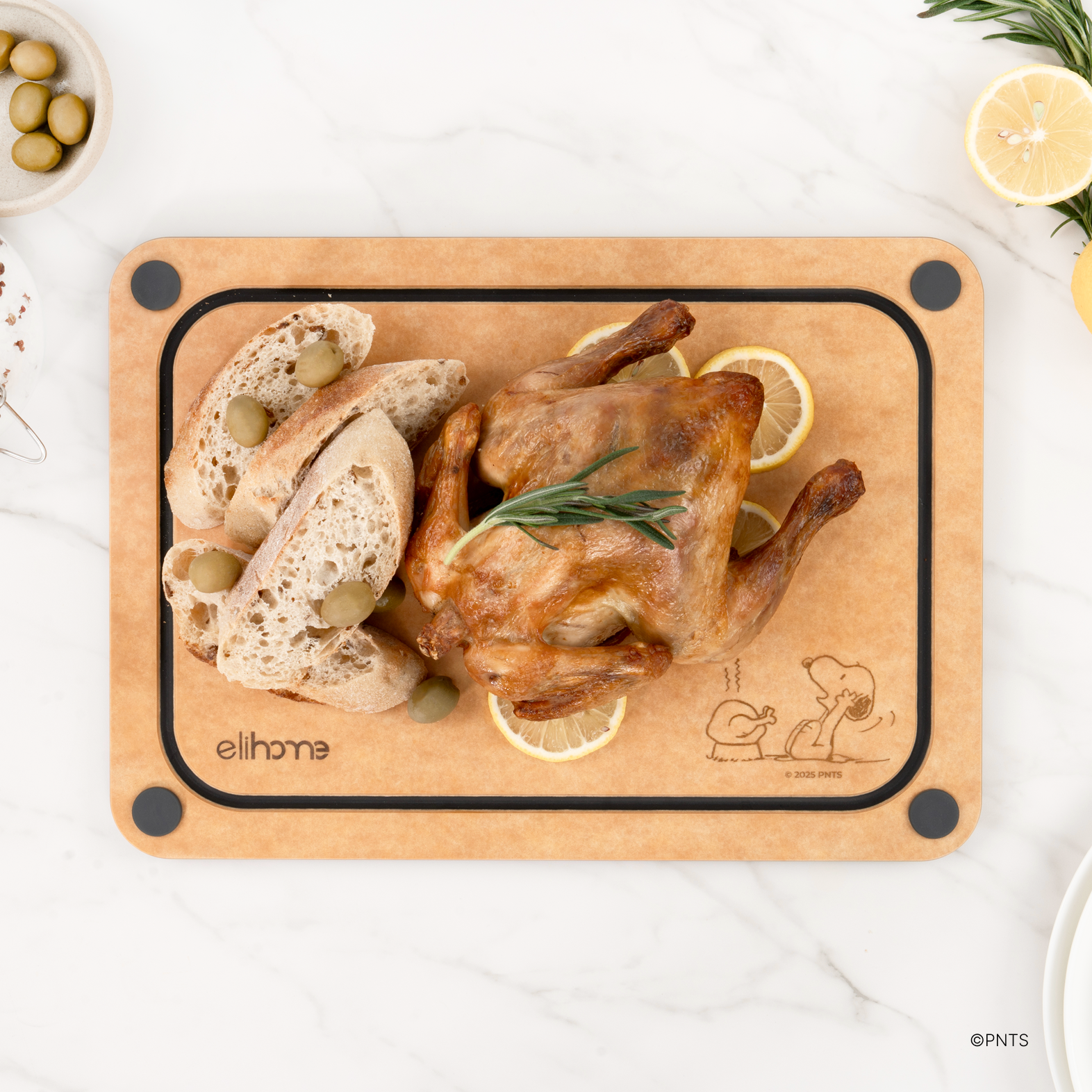 Natural side of the Elihome x Peanuts 4-in-1 cutting board with a roast chicken, bread and lemon slices