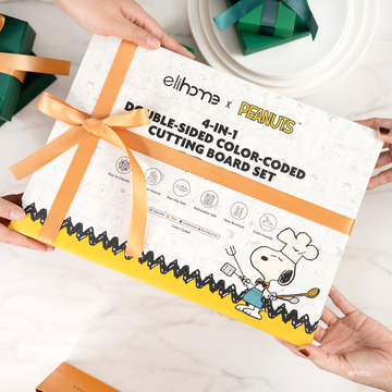 Elihome x Peanuts 4-in-1 Double-Sided Color-Coded Cutting Board Set gift box tied with an orange ribbon being handed over