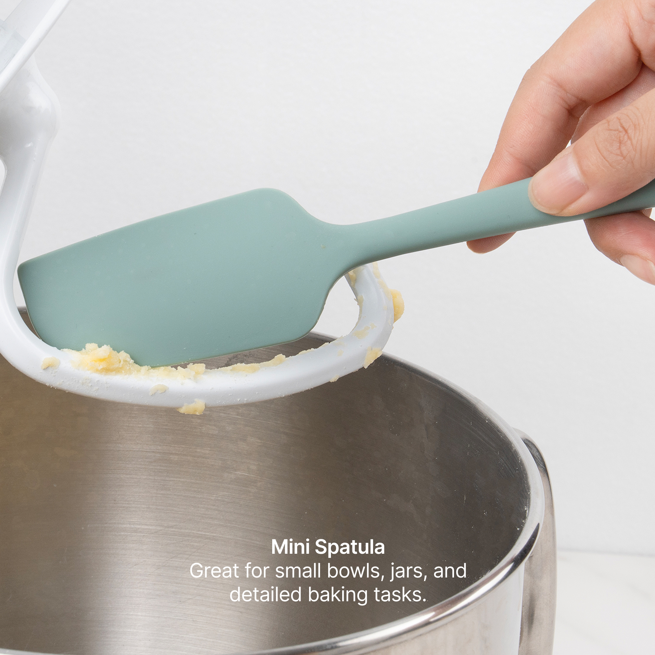 Hand using the Elihome x Peanuts Mini Spatula to scrape batter from a stand mixer bowl, great for small bowls, jars and detailed baking tasks