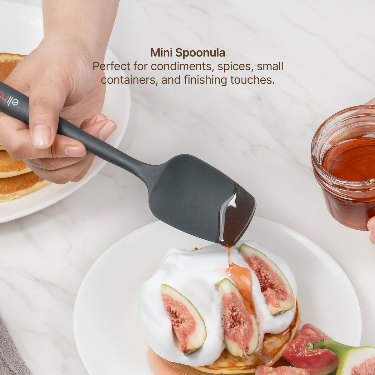 Hand using the Elihome x Peanuts Mini Spoonula to spoon honey over figs and cream, perfect for condiments, spices, small containers and finishing touches