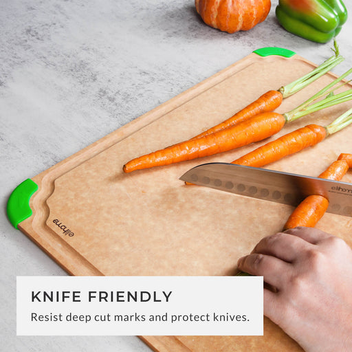 Hand slicing fresh carrots on a knife-friendly fiber wood cutting board with green non-slip corners, highlighting the surface that resists deep cut marks and protects sharp knives.