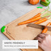 Hand slicing fresh carrots on a knife-friendly fiber wood cutting board with green non-slip corners, highlighting the surface that resists deep cut marks and protects sharp knives.