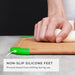A close-up side view of a hand pressing down on the cutting board to demonstrate the stability provided by the green non-slip silicone feet gripping the countertop surface, preventing shifting during use.